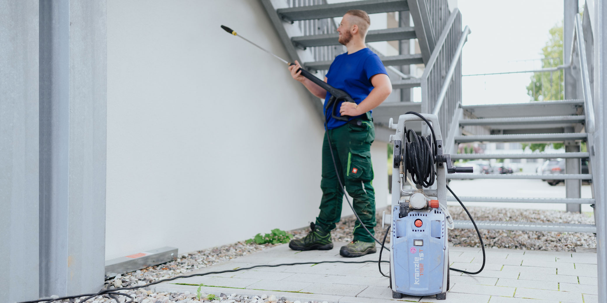 Ein Mitarbeiter reinigt eine Außentreppe.